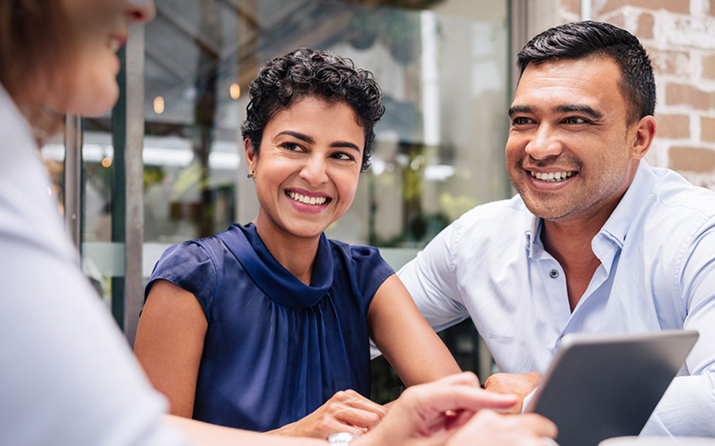 Three people sitting at a table smiling at each other